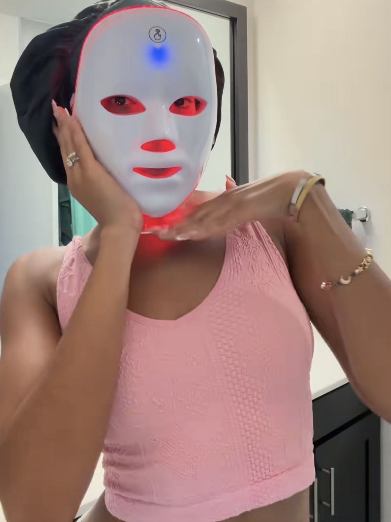 Kvinna i badrummet med duschmössa och LED-masken